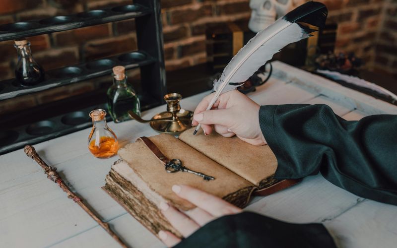 Historical quill pen writing on an aged notebook, surrounded by antique ink bottles, a vintage key, and candles, reflecting the timeless elegance and cultural significance of quills in writing history.