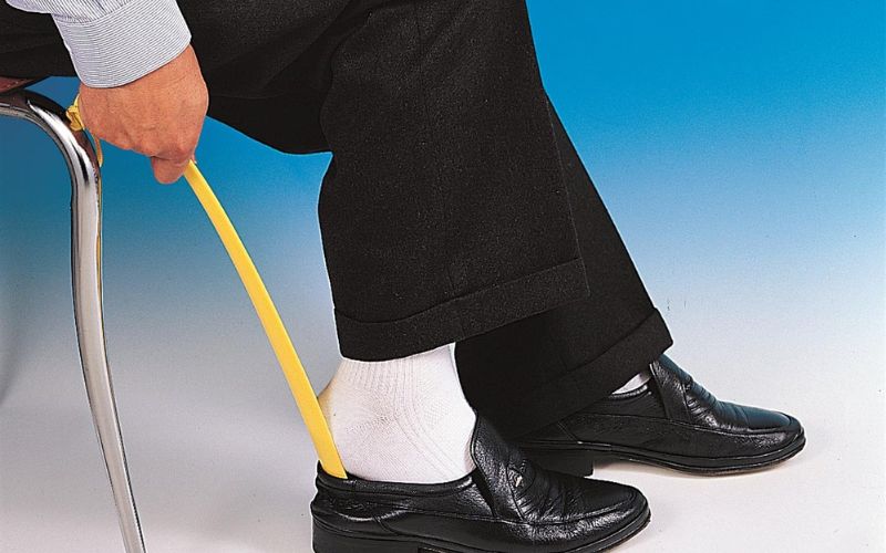 A man wearing shoes using shoe horn